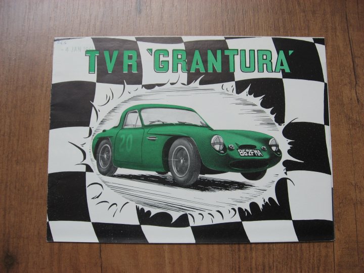 Sales Literature - Page 3 - Classics - PistonHeads - The image features a vintage poster with a green TRV 'Grantura' sports car, which appears to be either in motion or in a racing advertisement. The car is set against a checkered backdrop, likely representing a race or a classic rally, and is surrounded by dramatic lines and shapes that emphasize its presence. The poster has white borders with checkered patterns, giving it a historic and classic look. The bold green text on the top part of the poster clearly reads 'TVR Grantura', while additional smaller text likely provides additional information about the car or the event. The overall style of the image suggests a lean towards retro advertising for iconic race cars.