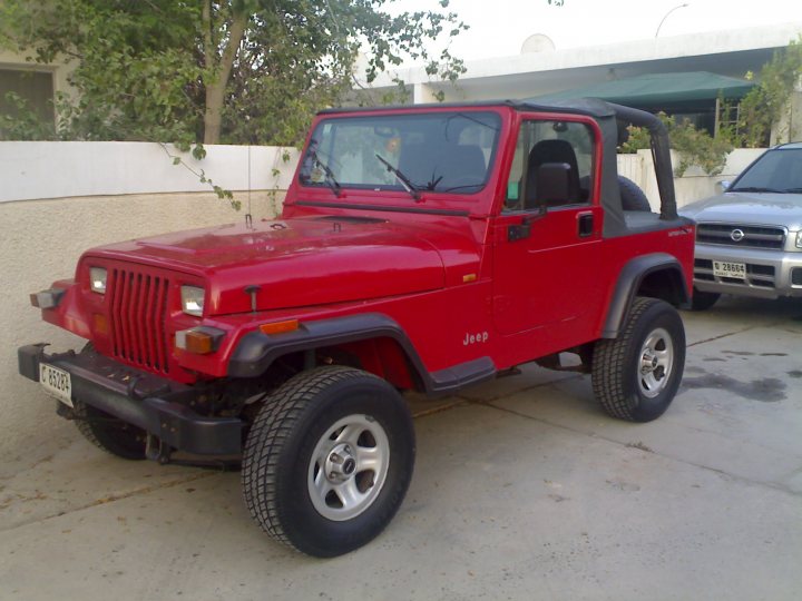 Project  Pepe - Page 1 - Middle East - PistonHeads - The image features a red Jeep parked on a driveway. The Jeep, which is an SUV, has four doors and is surrounded by lush greenery, indicating an outdoor, possibly suburban, setting. The vehicle is positioned at an angle, allowing for a clear view of its exterior. The Jeep's design is rugged and appears sturdy, which is typical of this type of vehicle. The driveway itself is paved and leads to a garage or parking area.