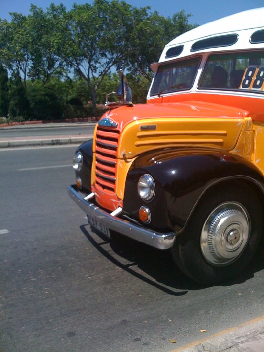 Pistonheads - The image features a vintage vehicle, possibly a bus, with a distinct orange and black color scheme. The bus appears to be in good condition and is navigating a street. The vehicle's design suggests an older model, with large headlights and a raised front: typical characteristics of a bus from a bygone era. In the background, there are trees and a clear sky, indicating that the photo was taken during a sunny day. The bus is the main focus of the image, and it is positioned in such a way that it takes up the majority of the frame, highlighting its prominence.