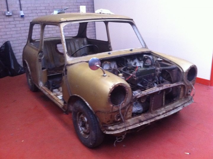 My 1960 Austin seven - Page 2 - Classic Minis - PistonHeads - The image showcases a vintage vehicle, specifically a beige car, parked indoors on a red floor. The car appears well-worn and weathered, indicating it has seen plenty of use or perhaps left exposed to the elements for some time. Despite the vehicle's apparent condition, a light glare on the windshield suggests the photograph was taken in a bright indoor environment. The expression "ROT-OF" that someone added to the image could imply the statement "surprisingly, nothing has been done since it first fell over." This conveys that despite the vehicle's tattered and ragged appearance, it might have retained some value to individuals who collect such vintage pieces.