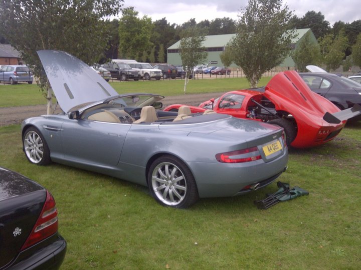 Pistonheads - The image portrays an outdoor setting on a grassy area. There are several cars parked together, including one with the hood open, suggesting some sort of maintenance or inspection. To the right, there's an Italian sports car that appears to be open and possibly in the process of being worked on. On the left, there's a car with special features, possibly a compromise between luxury and practicality. The image seems to capture a moment of car enthusiasts' activities, illustrating the diversity of vehicles and the atmosphere of a parking lot or a gathering point for automobiles.