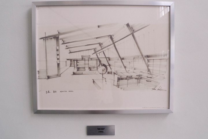 Studios Pinewood Pistonheads - The image showcases a framed black and white sketch hanging on a white wall. The sketch features a detailed architectural drawing of a metro station. Notably, the sketch identifies the work as "DR. L. W. PRITZEL 1956". The framed sketch is placed next to a small plaque, indicating its artistic value. The sketch's black and white color scheme creates a classic, nostalgic feel, further emphasized by the architectural style of the metro station depicted.