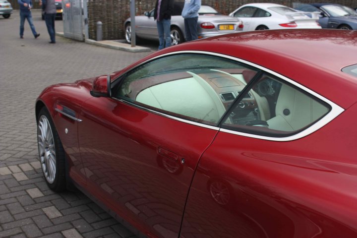 Pistonheads - The image depicts an urban setting, featuring a vibrant red BMW parked alongside a street. The car's design draws attention, with a prominent bonnet bulge and a sleek, aerodynamic body. In the background, other vehicles and pedestrians are visible, suggesting a busy city environment. The steep angle at which the photo is taken provides an upward gaze, giving the car a somewhat larger appearance.