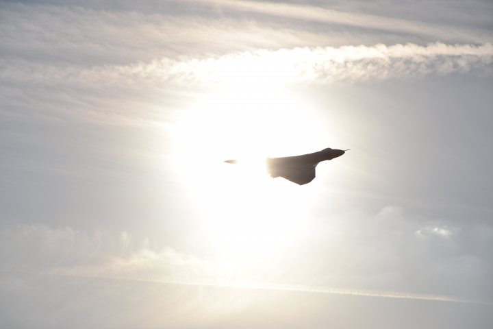 XH558.......... - Page 297 - Boats, Planes & Trains - PistonHeads - The image captures a dynamic bird in mid-flight against the backdrop of a striking sun. The bird, appearing as a dark silhouette, is sharply focused on the right, indicating its motion. The sun, partially obscured, creates an intense, bright centerpiece. The sky itself is a canvas of pale blue, adorned with wispy clouds that further enhance the soaring mood of the image. The overall scene conveys a sense of motion and freedom often associated with bird flight.