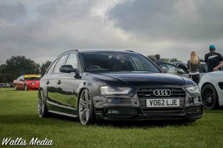 My Audi B8.5 S4 Avant Black Edition 2012 - Page 1 - Readers' Cars - PistonHeads - The image shows a black Volkswagen wagon parked on grass at an outdoor event. The car has customized modifications, including a widebody kit and a unique front bumper that features additional vents and design elements. It also appears to have aftermarket wheels. The vehicle is prominently displayed in the frame, occupying a significant portion of the image.

In the background, there are several individuals who seem to be attendees or participants at the event, although their activities are not clearly visible due to the distance from which the photo was taken. The setting suggests an informal gathering or car show, with no particular landmarks or architectural features in sight that would provide additional context about the location.

The overall atmosphere of the image is casual and relaxed, likely indicating a recreational or hobbyist activity, possibly related to automotive enthusiasts given the focus on the car and the surrounding people who share an interest in vehicles. The lighting and shadows suggest that the photo was taken during daylight hours under overcast skies.