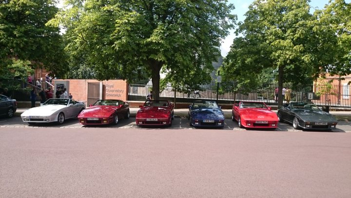 The Wedge Sausage Meet - Page 70 - Wedges - PistonHeads - The image depicts a row of classic cars parked in a row on the side of a street. There are four cars in total, ranging in colors from red to black and white. The cars are aligned in front of a building with brick walls, and there are trees in the background. The scene conveys a sense of orderliness and appreciation for vintage automobiles.