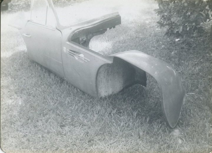 Early TVR Pictures - Page 36 - Classics - PistonHeads - The image showcases an old-fashioned car, predominantly grey in color, parked on the grass. The car's back left bumper is noticeably missing, indicating some level of wear and tear or possible damage. The car appears to be a vintage model, styled with a rear window and a bucket seat characteristic of an older era. The overall photograph has an aged appearance, suggesting it might have been taken some time ago. The car is parked in front of a tree, adding a touch of greenery to the scene.