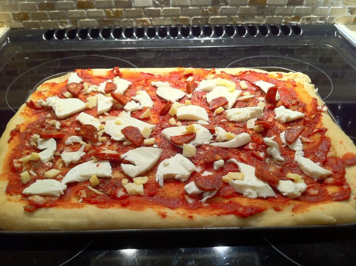 Pistonheads - The image captures a tantalizing frozen pizza, meticulously arranged in a neat grid pattern of eight equal pieces. Each piece is adorned with a rectangular slice of fresh white cheese, providing a stark contrast to the vibrant red of the pizza base. The pizza is resting on a cookie sheet, set against a backdrop of a pristine white wall, with an oven reflecting in the mirror beneath it. The anticipation is palpable, as if the pizza is longing for a delicious bake in the oven.