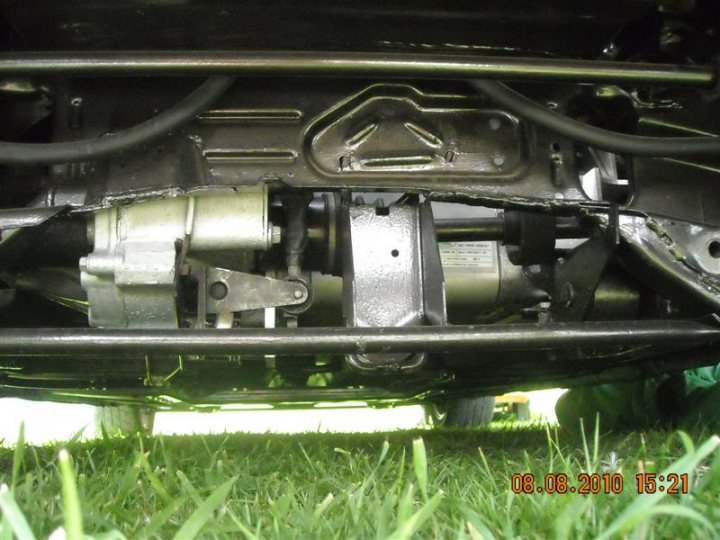 Pistonheads - The image is a photo showing a partial view of the undercarriage of a vehicle. There is a focus on a collection of mechanical parts and components, possibly related to the suspension system, with some parts bearing labels and markings. The components are constructed with metal, and there are visible signs of wear or metallic fatigue. The background is the ground with a bit of greenery and grass. There's a timestamp at the bottom right corner indicating the image was taken on August 8, 2010, at 15:21.