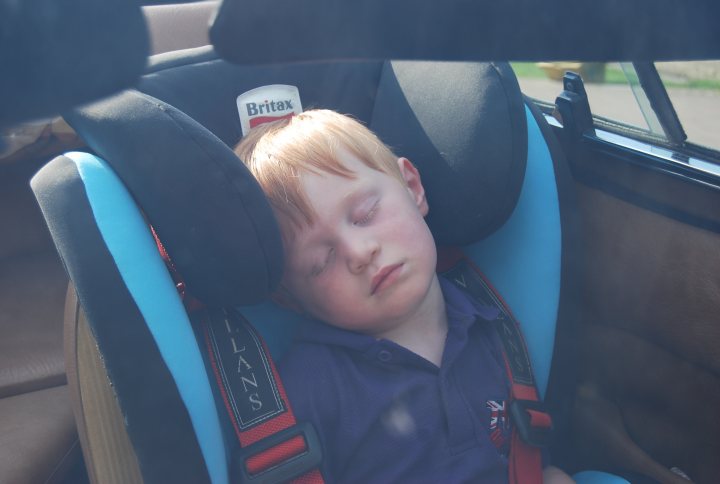 Hi from a newbie 3000S owner - Page 1 - Classics - PistonHeads - The image captures a serene scene of a young child, dressed in a blue shirt, fastened into a black and blue car seat. The child appears to be peacefully asleep, their head comfortably resting on the headrest of the seat. The seat is positioned in a car, identifiable by the visible dashboard and window in the background, suggesting the child is either on a journey or at rest after one. The overall atmosphere of the image is calm and tranquil, resonating with the soft, gentle slumber of the young passenger.