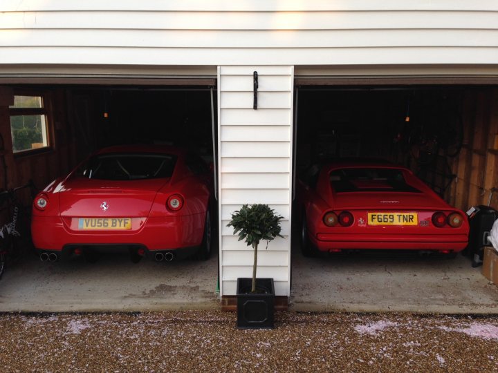 what's your favourite 'rear'? - Page 1 - Ferrari Classics - PistonHeads - The image captures a two-door garage housing two high-performance cars, a red one being a Maserati Spyder and the other a red Lamborghini. The garage appears well-maintained with a gravel floors. There are white walls and nearby pitch, suggesting frequent use. A house can be seen in the background, hinting at a residential setting.