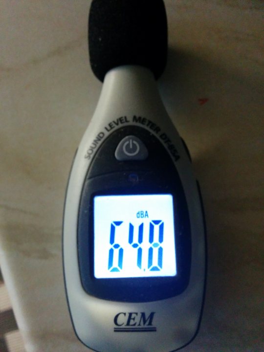 A close up of a person holding a cell phone - Pistonheads - This is an image of a dial thermometer. It has a digital display showing a temperature reading of "DBA 40," which is likely referring to the temperature in degrees Celsius, and that the current mode of operation is that of a digital, battery-operated (DBA) device. Below the screen, the word "CEM" is visible, possibly indicating the manufacturer or brand of the thermometer. The device appears to be resting on a surface with a pattern, which could be a table or countertop. The design and size suggest it's portable for on-the-spot temperature readings.