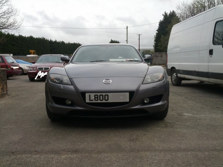 here's the new lemon...old lemon gone... - Page 1 - South Wales - PistonHeads - The image shows a gray Lexus L800 car parked on a concrete surface. The car is positioned in the center of the frame. To its right is a white cargo van, and to its left is a section of a brick wall. The setting appears to be in an urban or industrial area with other vehicles and a chain-link fence visible in the background.