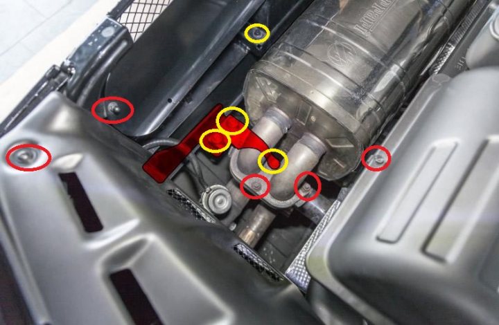 F430 part number help - Page 1 - Ferrari V8 - PistonHeads - The image displays the lower part of a vehicle's engine bay, exposed from an open hood. The area is filled with various mechanical components, including bolts and hoses. These components are visible through a layer of protective covers, which are peeled back, giving access to the lower engine components. The photograph is composed from an overhead perspective and is keen on capturing the engine's intricate details, utilizing a close-up angle that sharply focuses on these components.