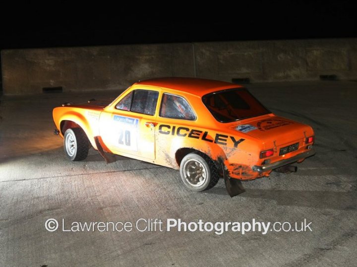 Legend Fires NW Stages 3-4 Feb - Page 1 - North West - PistonHeads - The image showcases a small, bright orange race car parked on a concrete surface at night. The car is labeled "CICELEY" with the number 40 prominently displayed on the side. It is equipped with large rear spoilers, suggesting that it is used for racing. There are also notable rear fender flares, which add to its racy appearance. The background is dark, which highlights the vibrant color of the car.