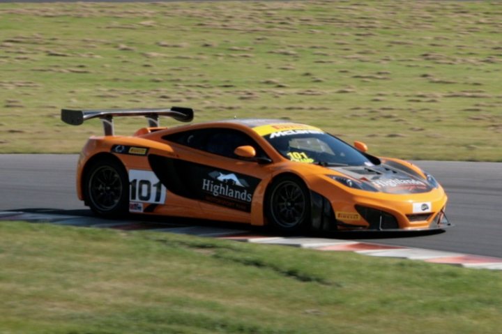 A red and white motorcycle parked on the side of a road - Pistonheads - The image showcases a high-performance orange sports car on a racetrack. It's moving at speed, with its rear wing pointed downwards, displaying a striking color contrast between the black and orange wings. The vehicle is prominently labeled "Highlands Motorsport," indicating the team or brand associated with it. The setting appears to be a dry track with grassy areas and a distinct pattern of red and white stripes on the asphalt, suggesting the presence of a pit lane or weight brakes. The car's angle and speed suggest movement on a curved part of the track.