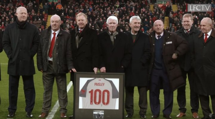 The Official Liverpool FC Thread [Vol 15] - Page 365 - Football - PistonHeads - The image is a photograph of a group of men posing together outdoors. They are dressed in winter attire, suggesting the photo was taken in cold weather. There is a sign among them, which appears to be associated with a rugby team, as indicated by the logo and number on it. The setting seems to be a football stadium or sports venue, as evidenced by the architectural features visible in the background. The style of the image is candid and informal, capturing a moment from what could be a team gathering, possibly celebrating a milestone or event related to their sport.