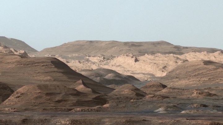 Fantastic Mars picture  - Page 1 - Science! - PistonHeads - This is an aerial view of a mountain range. The landscape is dominated by a series of large, rounded hills or mountain tops with eroded slopes and sides. There are no visible trees or vegetation, suggesting a possibly arid environment. The colors in the image are mainly earth tones, with varying shades of brown and gray indicating differences in the rocky surfaces. The ground appears flat in the foreground, suggesting a plateau or a wide valley floor.