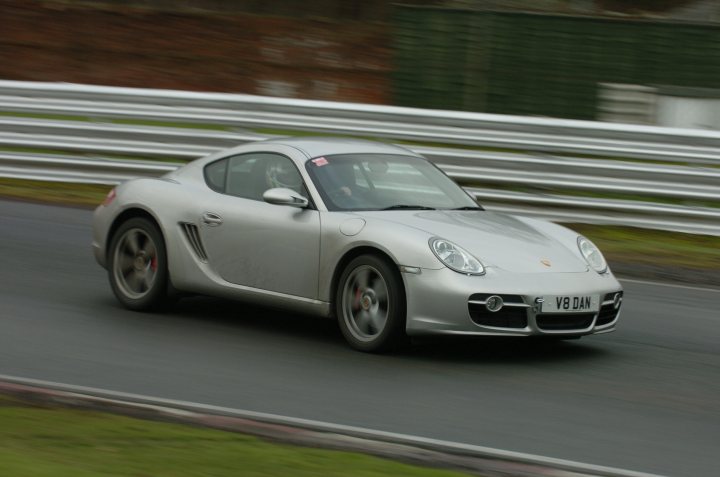 Boxster & Cayman Picture Thread - Page 42 - Boxster/Cayman - PistonHeads UK - The image is a photograph of a silver sports car on a racetrack, with visible tire wear indicative of high-speed use. The car is a Porsche 911 GT3, identifiable by its rear wing and the number 24 on the side. The track appears to be wet due to recent rain, as evidenced by the water droplets captured in mid-air. There are no visible people or spectators within the frame of this image. The photograph seems to have been taken from a distance, focusing on the vehicle in action rather than the surrounding environment.