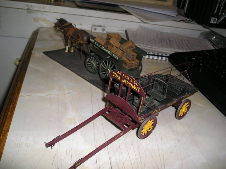 GB Chat thread - Hawker Tempest  - Page 10 - Scale Models - PistonHeads - The photograph depicts a small, vintage-styled model of a gas-powered horseless carriage, complete with foam wheels, a driver's seat, and text labels indicating "CCF HOUGHTON" and "COAL MERCHANTS." The model carriage is positioned on a blurred background, and a computer keyboard is visible in the lower right corner of the image, suggesting that the photograph was taken in an indoor space with a workstation. The toy is staged on a piece of paper, giving the impression that it is on display or a play setting.