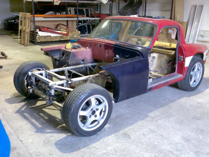 List of classic projects anywhere, who's doing what etc? - Page 3 - Classics - PistonHeads - The image showcases a small, vintage car that has been meticulously disassembled, revealing a red and black vehicle with a black fiberglass hood. The engine, car doors, and frame are all exposed, suggesting a restoration project in progress. The setting appears to be a garage or workshop, with various spare parts and tools scattered around, indicative of a space where automotive restoration takes place.