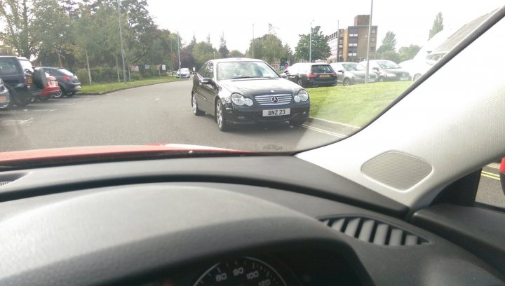 The BAD PARKING thread [vol3] - Page 202 - General Gassing - PistonHeads - This image captures a bustling scene on a city street, specifically from the interior of a car. The dashboard view shows the steering wheel and dashboard on the left side of the photo. In the background, various cars and a truck are parked along the street. Notably, there's a strong sense of contrast between the interior of the car and the exterior environment, creating a juxtaposition between private and public spaces.