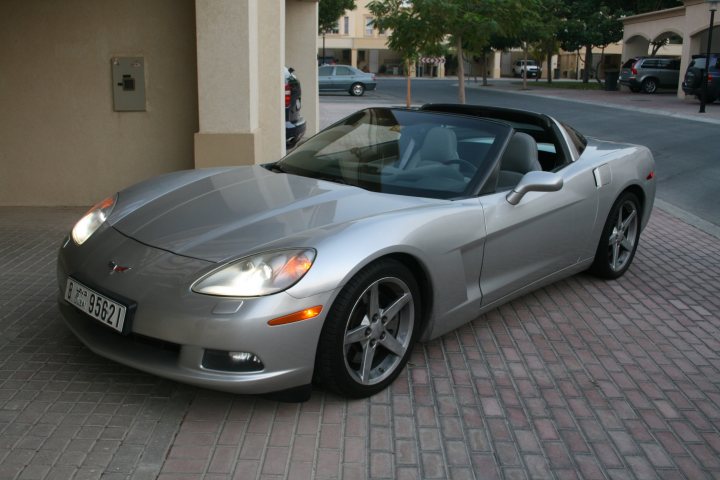 My PistonHeads : Show Car - PistonHeads - The image features a sleek, silver Corvette parked in front of a parking meter. The car's white license plate is clearly visible, and it has a convertible top that is currently up. The setting appears to be a sunny day in a suburban area, with trees in the background and a gray pathway on which the car is parked. The car's design and position suggest that it may be on display or attracting attention.