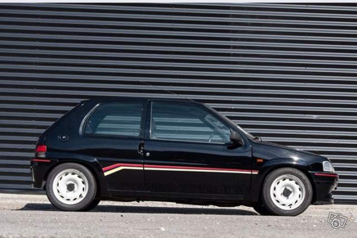 A car parked on the side of the road - Pistonheads - This image showcases a black and red sports car, elegantly parked by a large gray wall that gives an impression of an urban or industrial setting. The car's sleek design is accentuated by the contrast of its black body and the red stripe running down the side. The car's white wheels add to the visual appeal, standing out against the black tires. The car is positioned on the left side of the frame, its angle and location suggesting it may be ready for a drive.