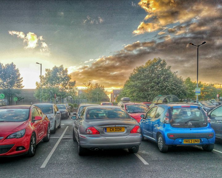 What C124PPY personalised plates have you seen recently? - Page 18 - General Gassing - PistonHeads - The image captures a bustling parking lot during what appears to be dusk. The lot is filled with multiple cars parked in rows, primarily consisting of hatchbacks and sedans. The sky is filled with gray clouds, suggesting an overcast day. Despite the gloomy weather, the lot is dimly lit, possibly due to the streetlights and car headlights. The setting suggests a commonplace urban scene.