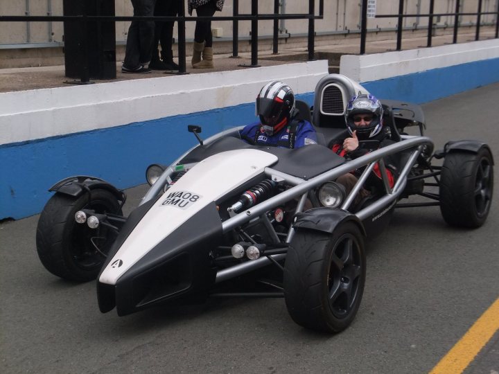 Pistonheads - The image captures a thrilling scene on a race track. There are two racing cars in the frame, both resembling Le Mans-style prototypes, suggesting they might be participating in a high-speed race or training session. The drivers, clad in full racing gear with helmets, are focused and appear to be in motion.

The drivers are holding the steering wheel firmly, showing their concentration and the intensity of the race. The cars exhibit features such as front and rear wings, which are typical in sports car racing for improving aerodynamics and reducing lift. 

The background of the scene features metal barriers, likely used for safety purposes, and it seems to be a well-maintained track. The metal barriers and the race cars together create an atmosphere of high-speed motorsport competition. The image conveys the adrenaline and excitement associated with professional or amateur racing.