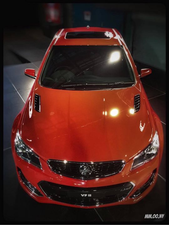 A red car is parked in a parking lot - Pistonheads - The image showcases a vibrant, red luxury car shining in a dimly lit showroom. The vehicle is parked on a sleek black floor surface, its design sleek and aerodynamic. The headlights are bright and well-defined, suggesting advanced lighting technology. The car features a visible Hyundai logo, indicating its make brand. The overall image presents a high-end, showcased vehicle, captured with enough detail to appreciate its design and the ambiance of the showroom.