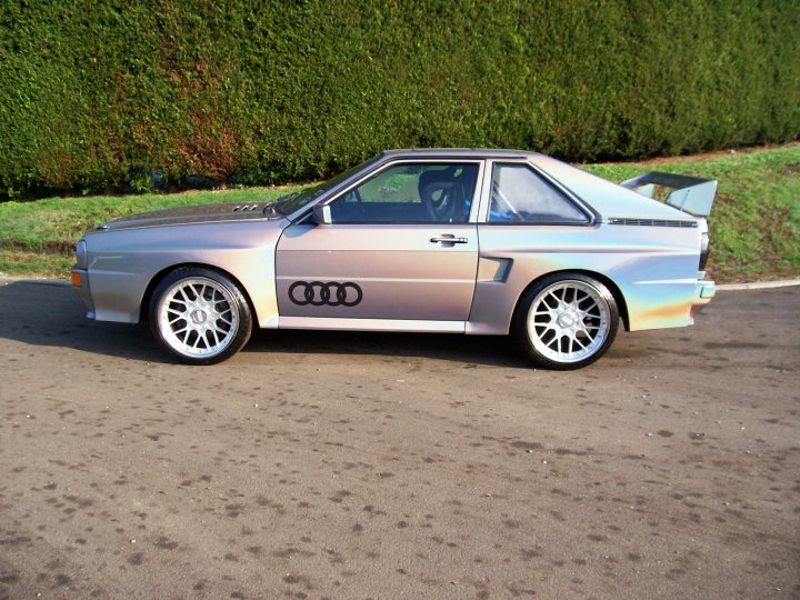 Pher Urgent Pistonheads Contact - The image depicts a vintage Audi coupe parked on a paved surface with a well-maintained, polished silver exterior. The car features distinctive wheel rims and a rear spoiler. The setting includes a manicured green hedge in the background, suggesting the photo might have been staged for aesthetic purposes. The precise make and model of the car are visible, and it shows signs of a recent cleaning or polishing.