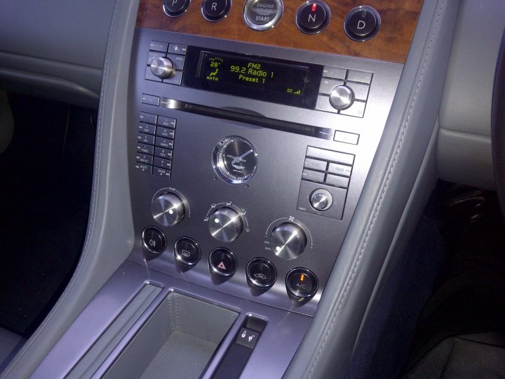 Pistonheads - The image showcases a car's center console, which is set in wood. The console includes a digital display screen that displays various pieces of information such as the time and the vehicle's speed, 0 km/h. There are also temperature and other controls nearby, suggesting an older model vehicle, potentially a limousine. Adjacent to these controls, one can see the interior door handle, which matches the wood interior design. The car's interior is viewed from the driver's perspective, and a proximity switch on the console is illuminated, indicating that the driver is ready to open the door.