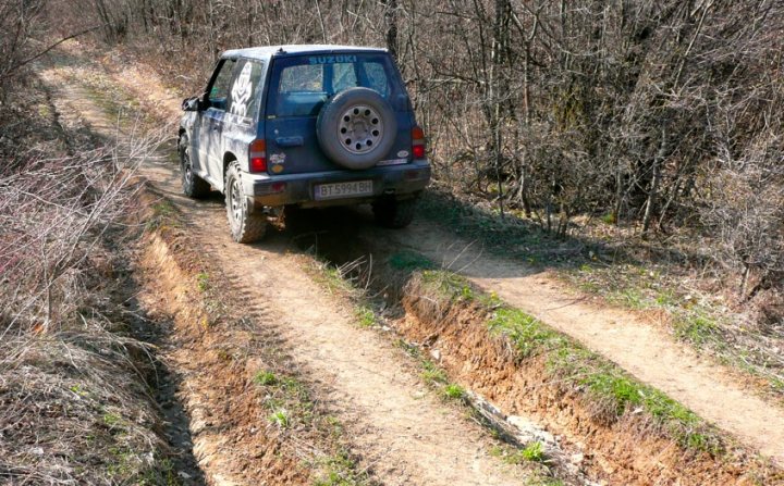 Winters over... Big chunky proper tyres back on... - Page 1 - Off Road - PistonHeads - The image captures an outdoor scene featuring a **blue SUV** parked on a **dirt road**. The car is sporting a **spare tire** mounted on the trunk. The road is flanked by **trees**, suggesting a natural setting. The overall atmosphere of the image is serene and rural.