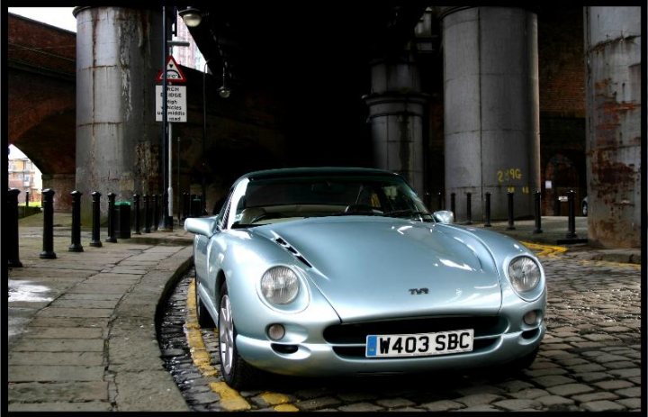 Photoshoot Locations - Manchester / Salford / Trafford Park - Page 1 - North West - PistonHeads - The image depicts a silver, two-door sports car parked on a cobblestone street. The car is positioned in front of an overpass, suggesting it is in an urban setting. The vehicle features a curved front and a sleek profile, indicative of its sporty design. A distinctive number plate identifies it as a "W403 SBC," likely serving as a reference for maintenance or identification purposes. The overall composition of the image, characterized by its focus on the vehicle and the overpass, captures the elegance and sophistication of the car in its environment.