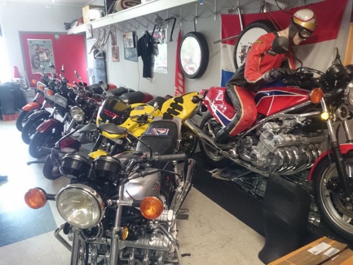 A picture a day....biker banter (Vol 4) - Page 505 - Biker Banter - PistonHeads - The image captures a collection of motorcycles parked neatly in an indoor garage. There are at least six motorcycles visible, parked side by side with their front ends facing towards the camera. The motorcycles vary in design and color, showcasing a diverse selection. The garage itself appears quite spacious, with visible racks and an arrangement of larger and smaller motorcycles. The ambiance is professional and well-maintained, suggesting this might be a showroom or a dedicated collector's garage.