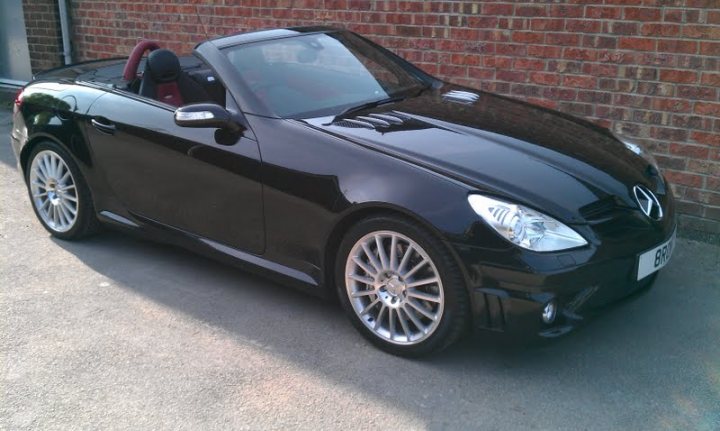 Show us your Mercedes! - Page 9 - Mercedes - PistonHeads - This image depicts a small, black sports car parked next to a red brick wall. The car has a sleek and shiny finish, with black wheels, which stand out against the car's glossy bodywork. There are no visible distinguishing marks or text on the car, and the environment suggests an urban setting but gives no indication of the time of day. The focus is on the car, which is the main subject of this photograph.