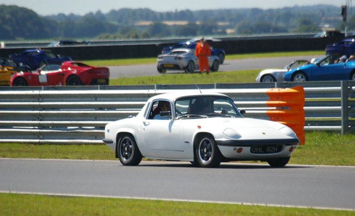 Snetterton Lotus Festival 25/26 June - Page 1 - General Lotus Stuff - PistonHeads - In the image, there is a thrilling scene on a racetrack where a white sports car is the center of attention, driving on a track surrounded by a starting line with orange cones. The track itself appears asphalt, and the weather is clear, suggesting ideal racing conditions.

There are spectators watching the race from the stands, and they seem to be engrossed in the excitement. A total of 8 cars have started their race, and they are variously positioned on the track, each with drivers ready to take off at the starting line.

On the left side of the image, there are cars neatly parked, possibly belonging to the race competitors or spectators. The environment appears to be an organized racing event with necessary infrastructure in place for the event. The overall atmosphere in the image reflects the anticipation and adrenaline typical at a racing event.