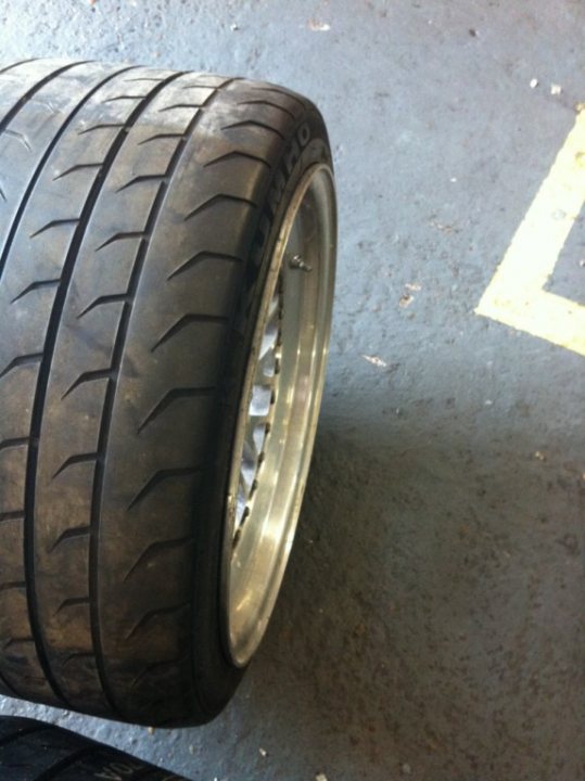 A close up of a motorcycle parked in a parking lot - Pistonheads - The image shows a tire placed on a ground marked with yellow lines that are likely to be safety or parking markings. The tire exhibits a tread pattern designed for traction and has the brand name inscribed on the sidewall. It appears to be new or in good condition. The wheel rims are metal with a shiny finish.