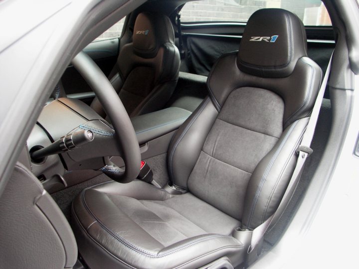 How about some ZR-1 photos to cheer you up? - Page 1 - Corvettes - PistonHeads - The image presents the interior of a car, specifically focusing on the driver's seat. This seat is an upgraded, black and silver sports seat, which appears to be luxurious and designed for performance driving. The seat is positioned alongside the center console, where a gear shift lever can be seen, suggesting that this car is a manual transmission model. The upholstery has a glossy finish, adding to the sense of sophistication and quality of the vehicle.