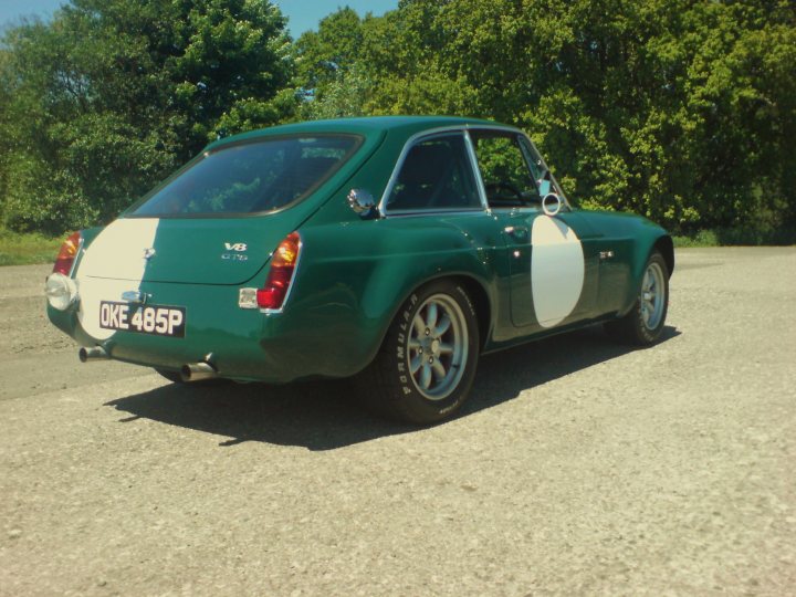 Pistonheads Mgb Sebring Conversion - The image depicts a green and white classic car parked on a gravel surface. The car appears to be manufactured by Riley Cars, as indicated by the emblem on the hood. Its design includes a distinctive split-windshield and a luggage rack. The license plate says "OKE 485P," suggesting that this car might belong to someone who values vintage vehicles. The background is less defined due to the focus on the car, but there are trees visible, indicating a rural or semi-rural setting.