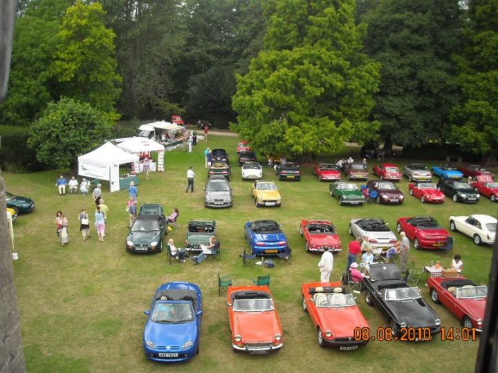 Pistonheads - The image showcases a vibrant auto show held on a picturesque lush lawn. Various cars, trucks, and buses are neatly displayed, boasting a range of colors and models. The attendees, who are scattered around the area, appear to be enjoying the event, adding a lively atmosphere to the scene. The whole scene is set against a backdrop of lush green trees, making the setting even more outdoor heaven.