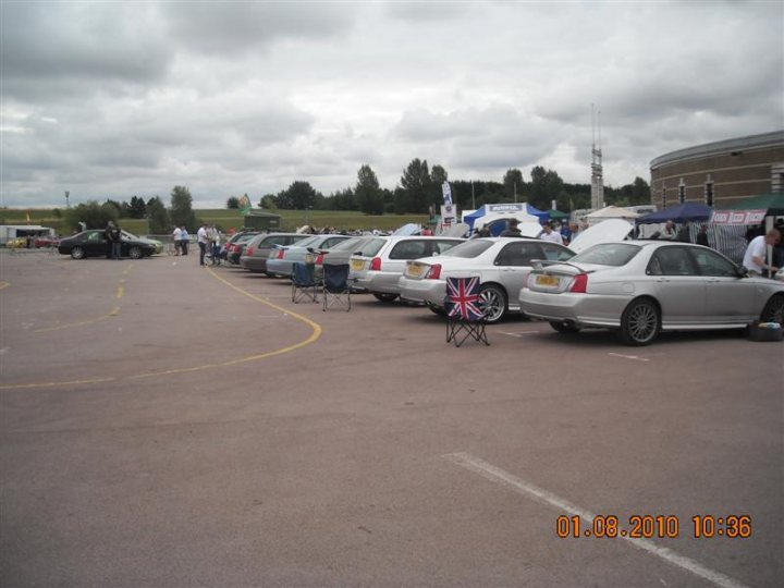 Pistonheads - The image captures a bustling scene in a parking lot on what seems to be a cloudy day. The lot is filled with numerous vehicles of various shapes and sizes, all parked neatly in rows on the asphalt. Interspersed among these cars, there are also several tents pitched, adding a touch of color and activity to the scene. Amidst the vehicles, a few chairs can be spotted, possibly indicating a social gathering or event. The presence of these chairs suggests that there might be some sort of informal gathering or sale occurring. Because the date on the image indicates the Feast of St. John Vianney (October 4th), it's plausible that there's a religious event taking place that day.