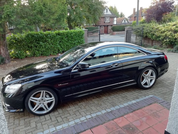 Mercedes-Benz CL500 - Page 4 - Readers' Cars - PistonHeads - The image shows a black Mercedes-Benz car parked on a driveway. It is a sleek, high-end vehicle with a shiny exterior. The car features distinctive alloy wheels and a visible rear spoiler. The setting includes a house with a white front door in the background, suggesting a suburban residential area. There is no visible text or branding in the image.