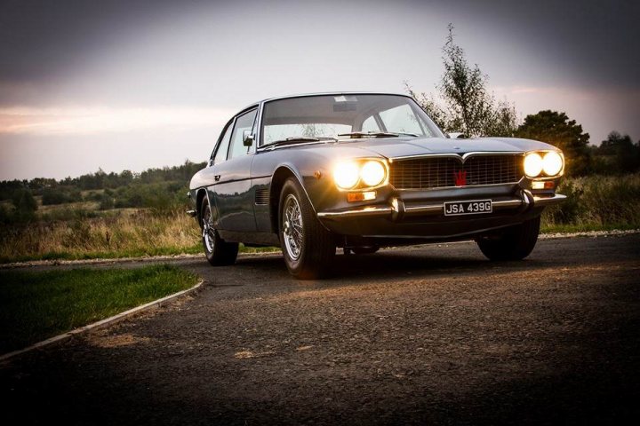 Lets see a picture of your classic(s) - Page 282 - Classic Cars and Yesterday's Heroes - PistonHeads - The image shows a vintage car parked on the side of a road. It's an evening scene with a sky that transitions from the light of sunset to the darkness of night. The car has round headlights and appears to be a British sports car, given the prominence of the round front badge. The license plate has parking-specific registration details, indicating that the photo might have been taken several years ago.