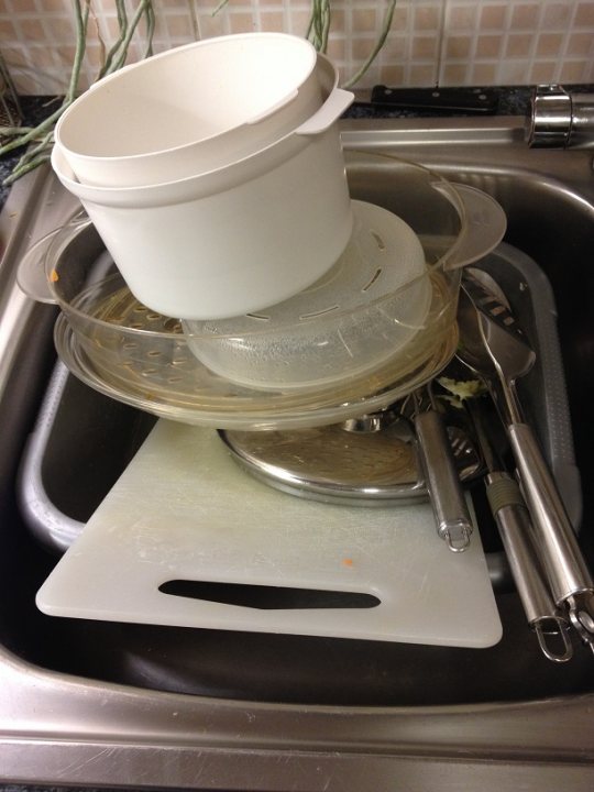 Pistonheads - The image shows a kitchen sink filled with various kitchenware. At the top of the sink, there is a white bowl or pot that appears to be empty except for its lid. Below it, there's a clear plastic lid set inverted upside down. A stainless steel plate rests on top of the lid, and underneath it, another stainless steel object, which could be a pan or a cutting board, lies inverted position. The sink itself appears to be metallic, and the countertop in the background is tiled, suggesting a kitchen setting. The overall atmosphere of the image is quite ordinary and everyday, reflecting a typical post-dishwashing scenario.