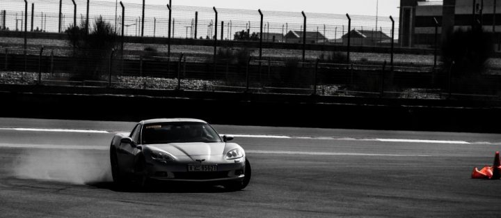 New 'Vette owner saying Hi - Page 1 - Corvettes - PistonHeads - The image captures a tense moment on a race track. A silver car, seemingly an Audi, is at the peak of a curve, trailing smoke due to its speed. The driver is leaning into the turn, showcasing their incredible piloting skills. In the background, fences are visible, marking the boundaries of the track, while a building can be seen in the distance, adding context to the location. This high-speed, action-packed scene encapsulates the thrill of motorsports.