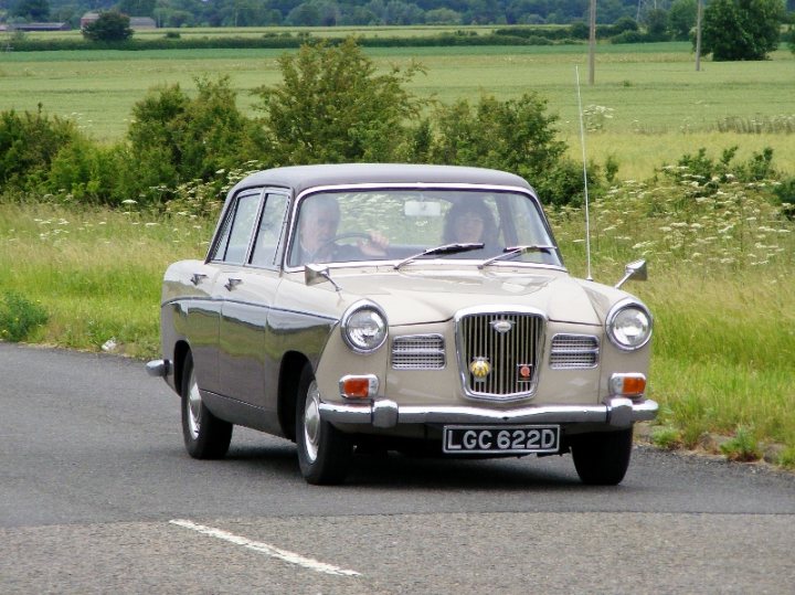 Herts, Beds, Bucks & Cambs Spotted - Page 332 - Herts, Beds, Bucks & Cambs - PistonHeads - The image captures a scene on a road, with a vintage car as the primary subject. The car is designed like a station wagon, and it has a distinct, shiny exterior, suggesting it might be made of material like tin or chrome. It's driving down a paved road, with the driver visible through the vehicle's rear window. Surrounding the car, the setting features grass on both sides of the road, which appear to be well-maintained. The road itself is lined with trees and bushes, adding to the picturesque quality of the scene. The vintage car gives a sense of nostalgia and charm to the overall image.