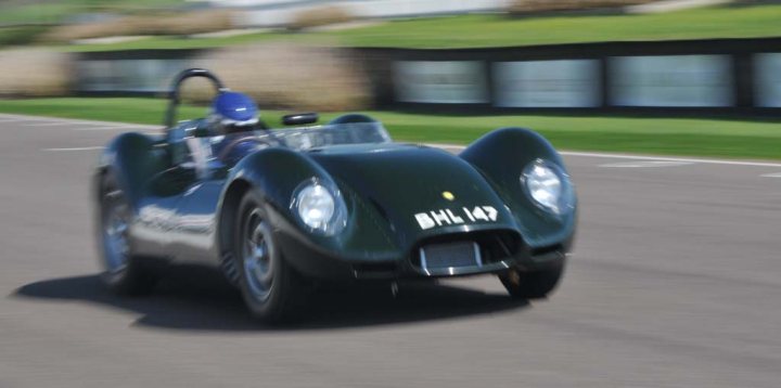 Goodwood yesterday...... - Page 1 - Classic Cars and Yesterday's Heroes - PistonHeads - The image portrays a vintage, green, open-top sports car in motion. The car is on a paved race track, with the blurry background suggesting speed. The word "BHL 147" is visible on the front of the car, which may be the registration or a specific model designation. The car has a crewman at the front, driving and controlling the vehicle during a race or demonstration.