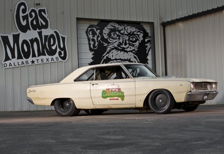 BBC Top Gear 2019 Thread - Page 189 - TV, Film & Radio - PistonHeads - The image shows a vintage car parked in front of a building. The car is beige with white decals, one of which features an elephant graphic. The license plate on the car reads "89701." On the building, there is signage for "GAS MONKEY" and "DALLAS, TEXAS," indicating that it's a shop or business related to vehicles. The setting appears to be in an urban environment, and the style of the image suggests it might be used for promotional purposes.